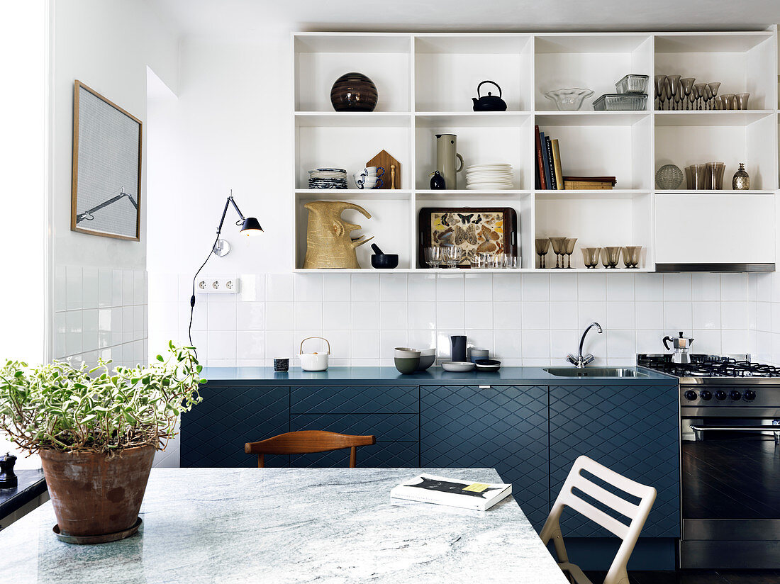 Eat-in kitchen with dark blue kitchenette and open shelves
