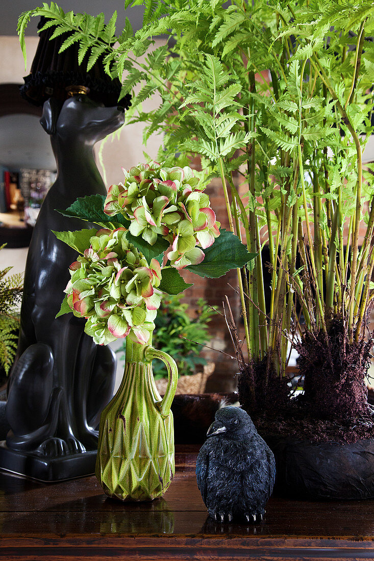 Hortensie, Zimmerpflanze und Tierskulpturen auf Holzablage