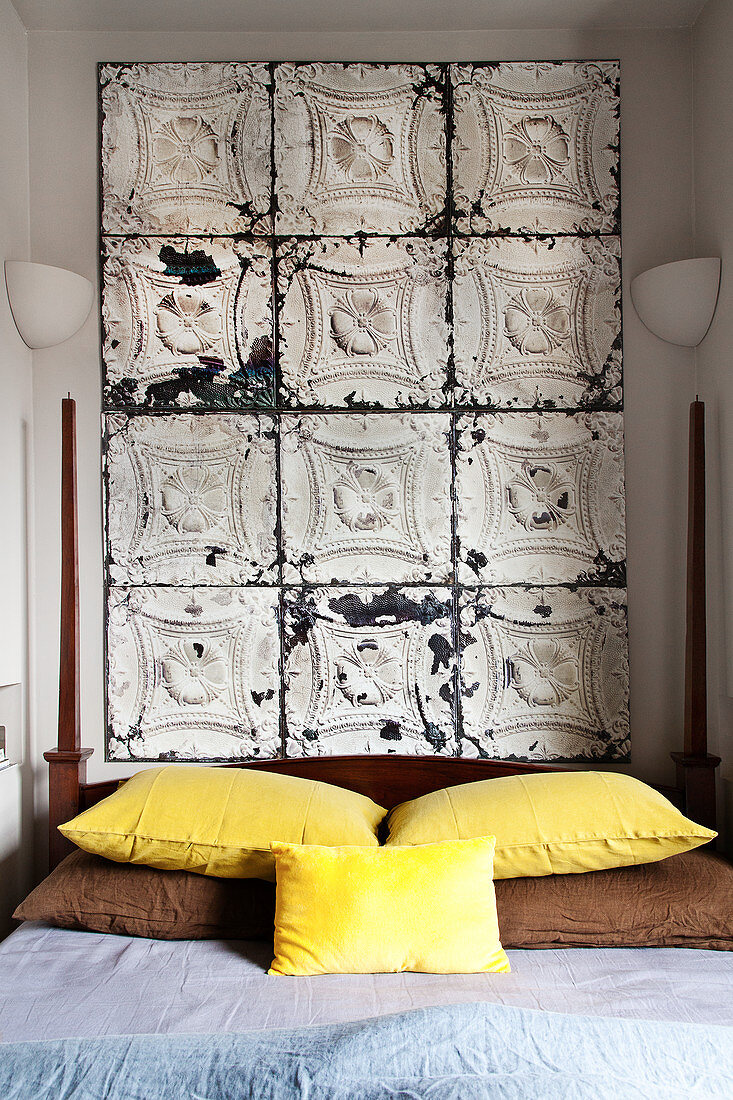 Cushions with brown and yellow covers on a double bed, above stucco tiles