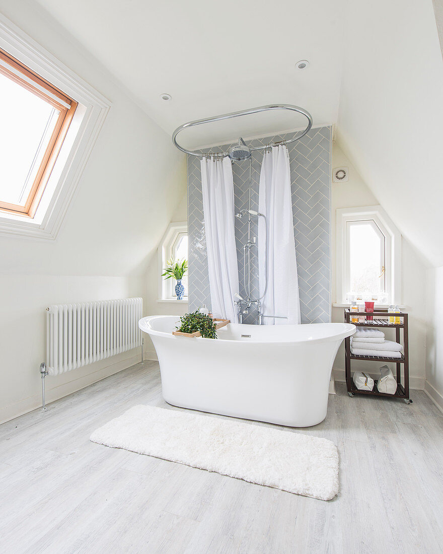 Free-standing bathtub in elegant attic bathroom with sloping walls