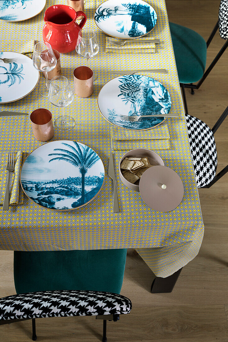 Plates with exotic motifs on set table in mid-century style