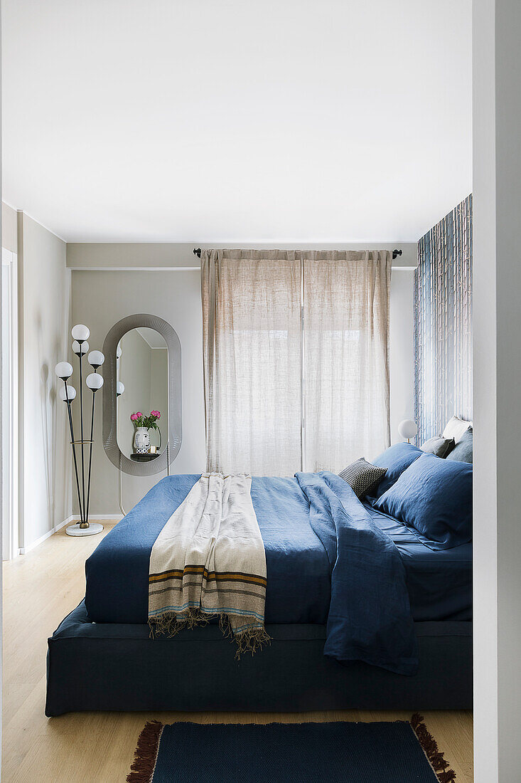 View into bedroom with dark blue bed and grey walls