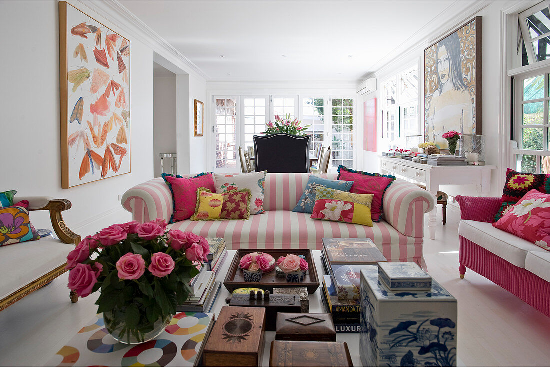 View past books and boxes on coffee table to pink-and-white striped sofa
