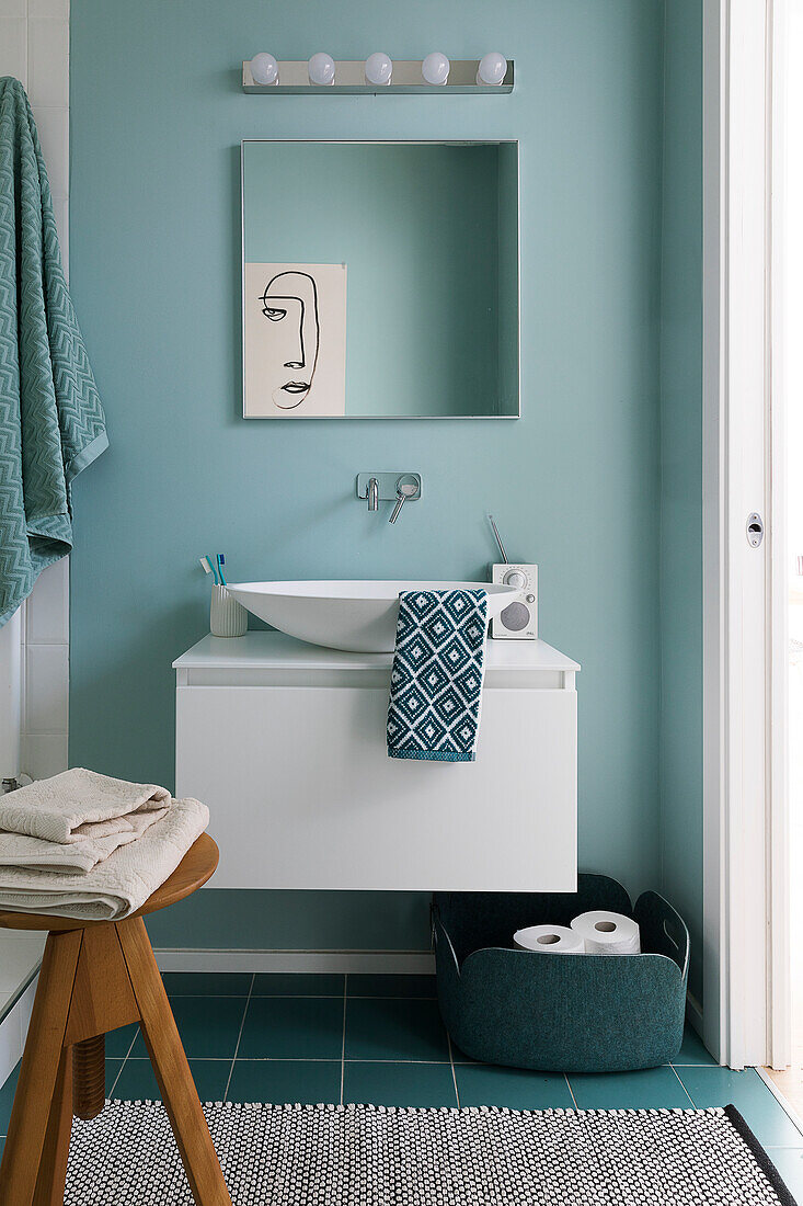 One-line drawing seen in mirror above sink in pale blue bathroom