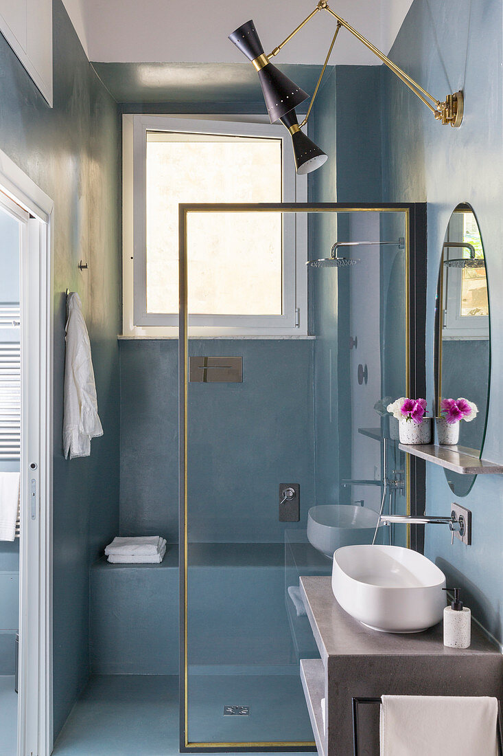 Dusche mit gemauerter Sitzbank hinter Glasabtrennung im Bad mit graublauer Wand