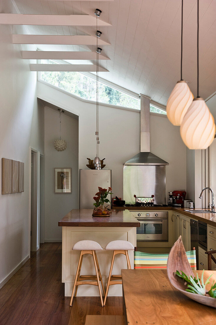 Modern, open-plan, U-shaped kitchen in high-ceilinged room with sloping ceiling
