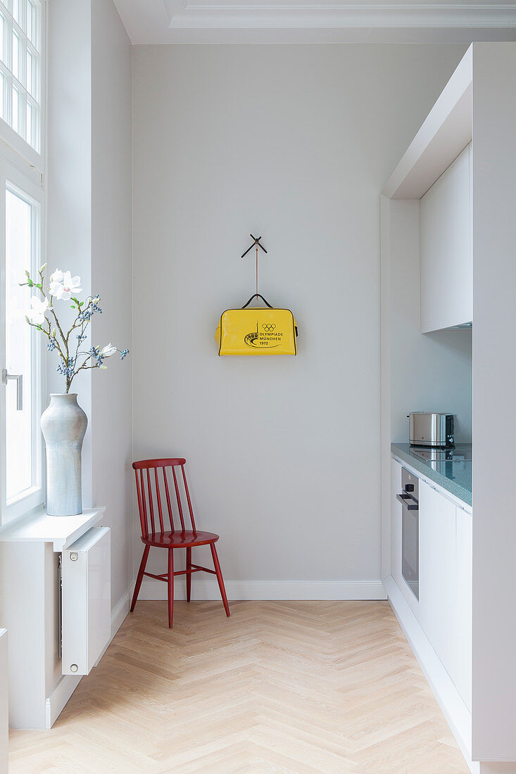 Stuhl vor schlichter Einbauküche in Altbauwohnung, Tasche an der Wand