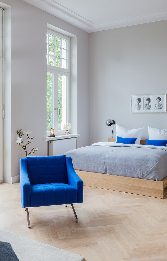 Blauer Polstersessel vor Doppelbett im Altbau-Schlafzimmer