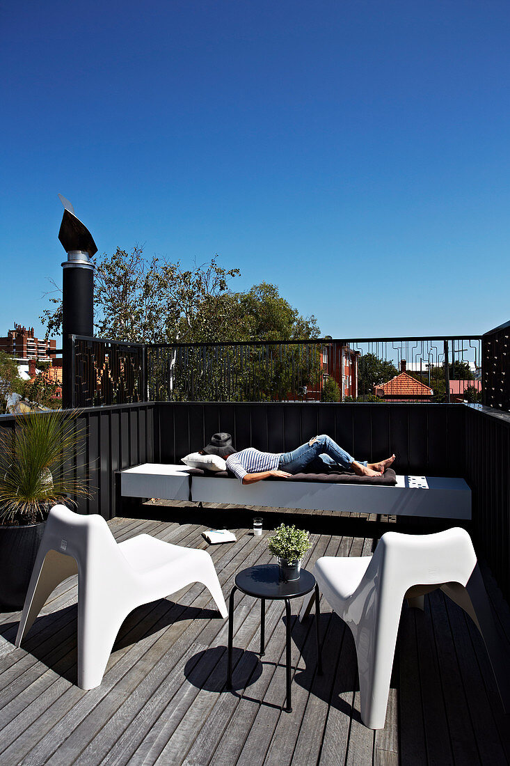 Woman relaxes on roof terrace with designer furniture