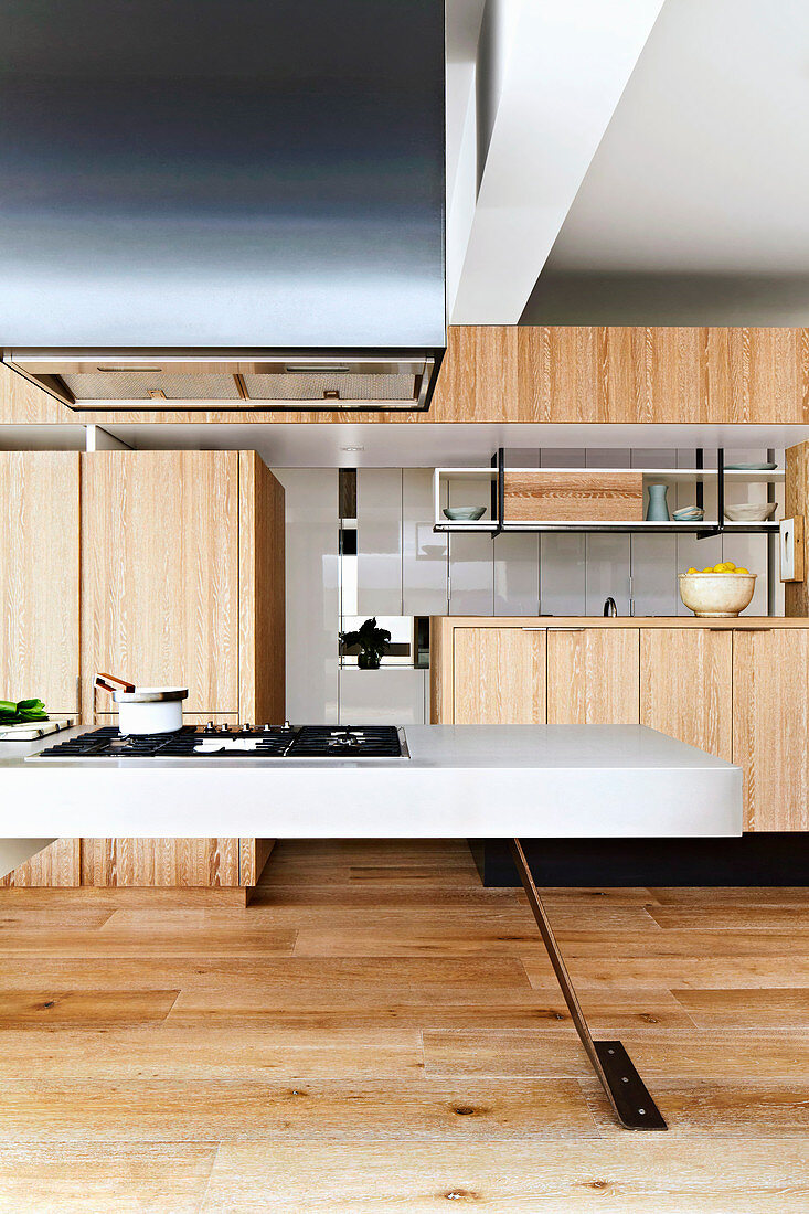 Einbauküche mit Holzfronten und weißer Kochinsel in offenem Wohnraum