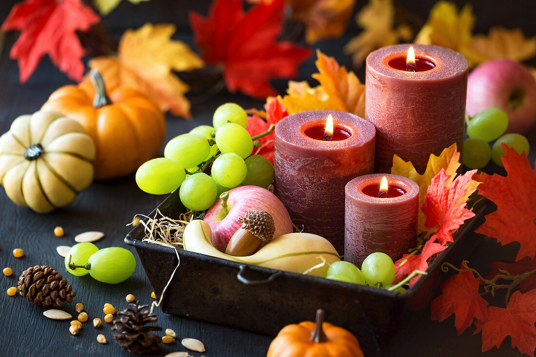 Erntedank-Dekoration mit Kerzen, Herbstfrüchten, Kürbissen und Laublättern