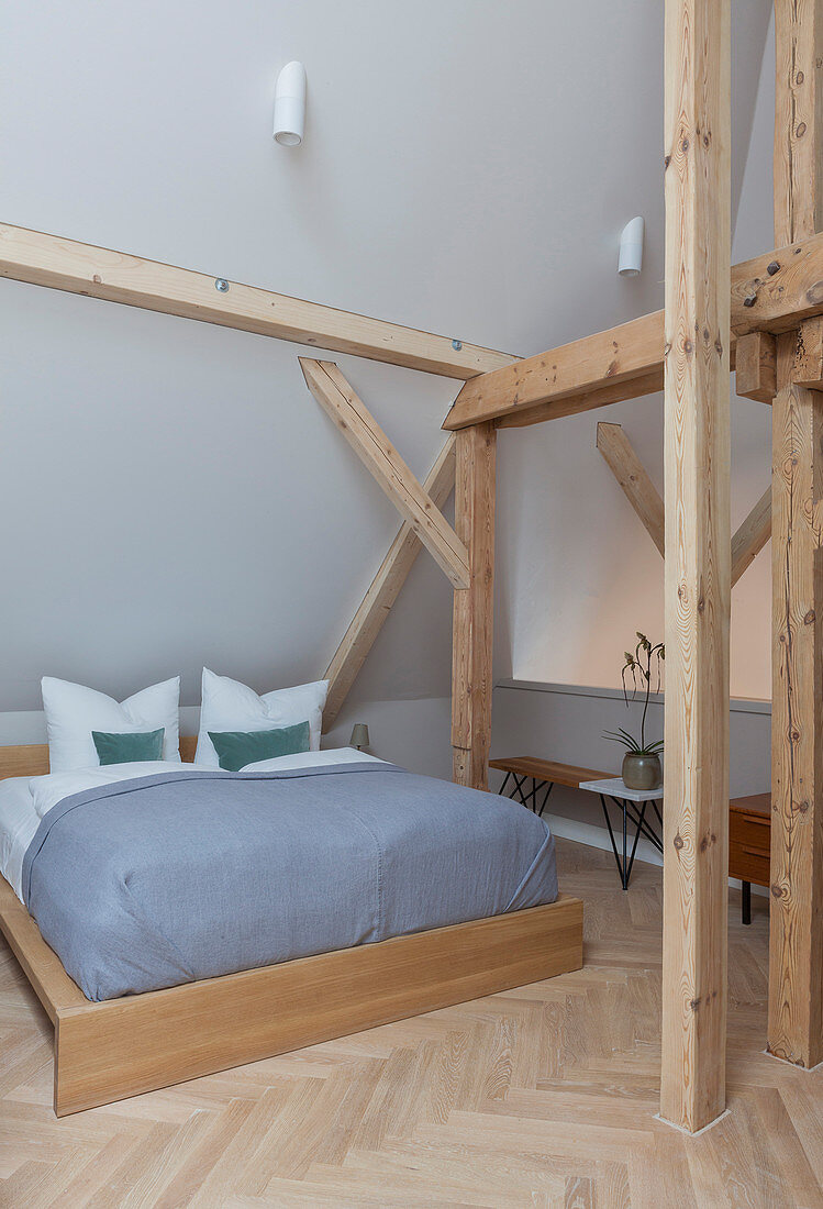 Wooden double bed in bedroom of period apartment with wooden beams