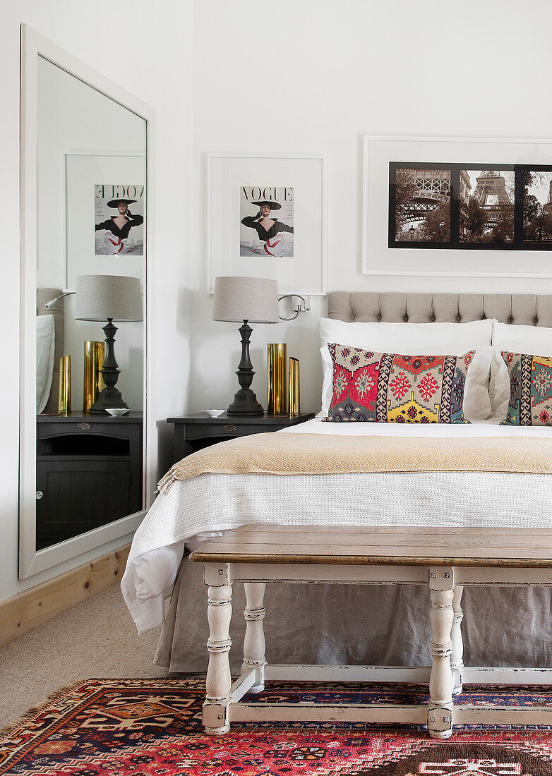 Doppelbett mit Kissen in Kelim-Look und Wandspiegel im Schlafzimmer