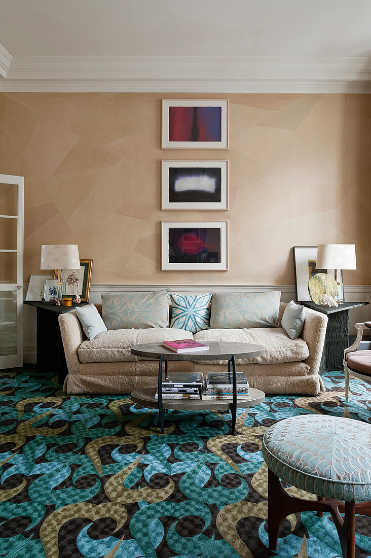 Wohnzimmer mit beigefarbener Seidentapete, Sofa und Musterteppichboden