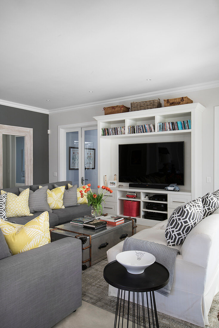Graue Sofagarnitur, Metallkoffer als Couchtisch und Regal mit Fernseher im Wohnzimmer