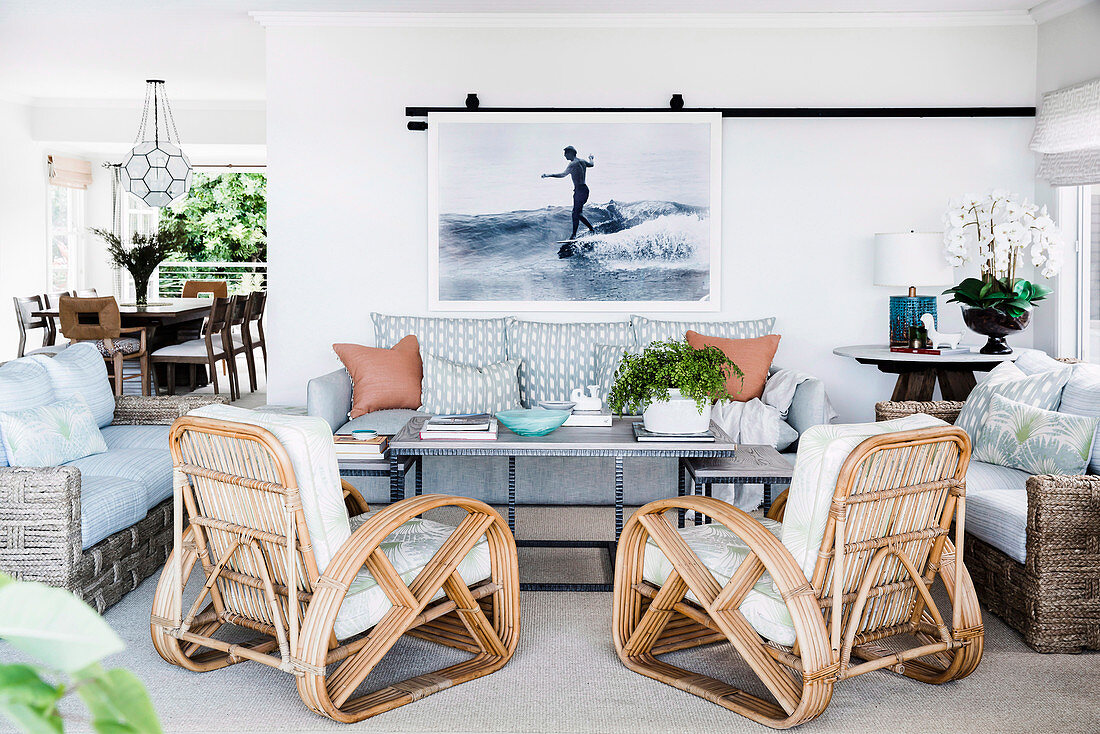 Designer-Rattansessel und Sofas um Tisch in offenem Wohnraum