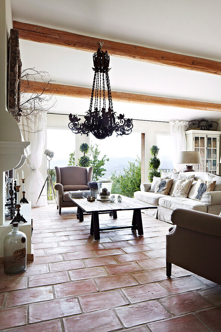 Wohnzimmer mit schmiedeeisernem Kronleuchter und Terracottofliesen in französischem Landhaus