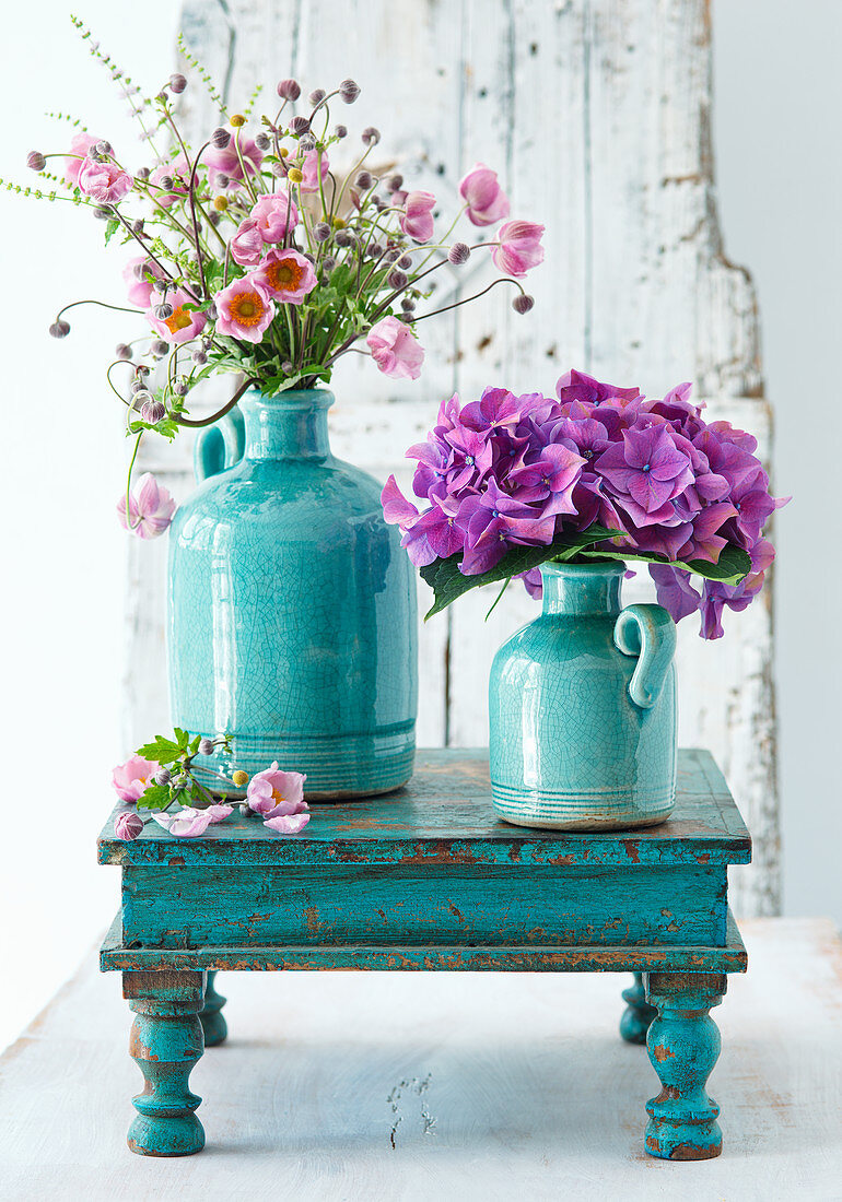 Herbstanemonen und Hortensien in türkisfarbenen Vasen