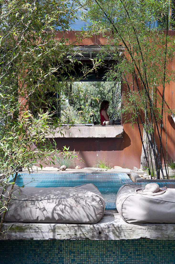 Bodenkissen am Pool vor dem Haus mit rostiger Fassade