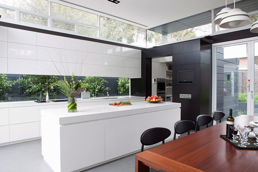 Holztisch vor minimalistischer Einbauküche mit Fensterbändern