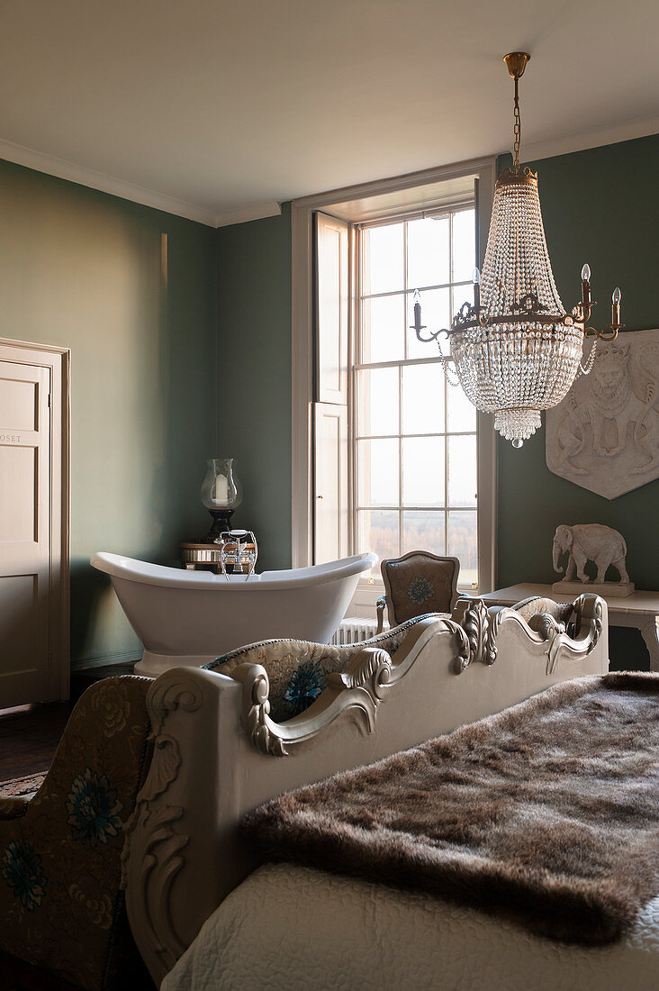 Copper bath in green guest room with crystal chandelier