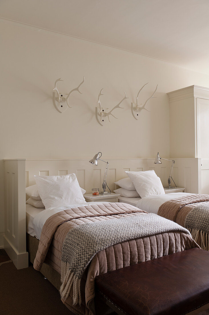 White twin bedroom with mounted antlers, quilts and rugs