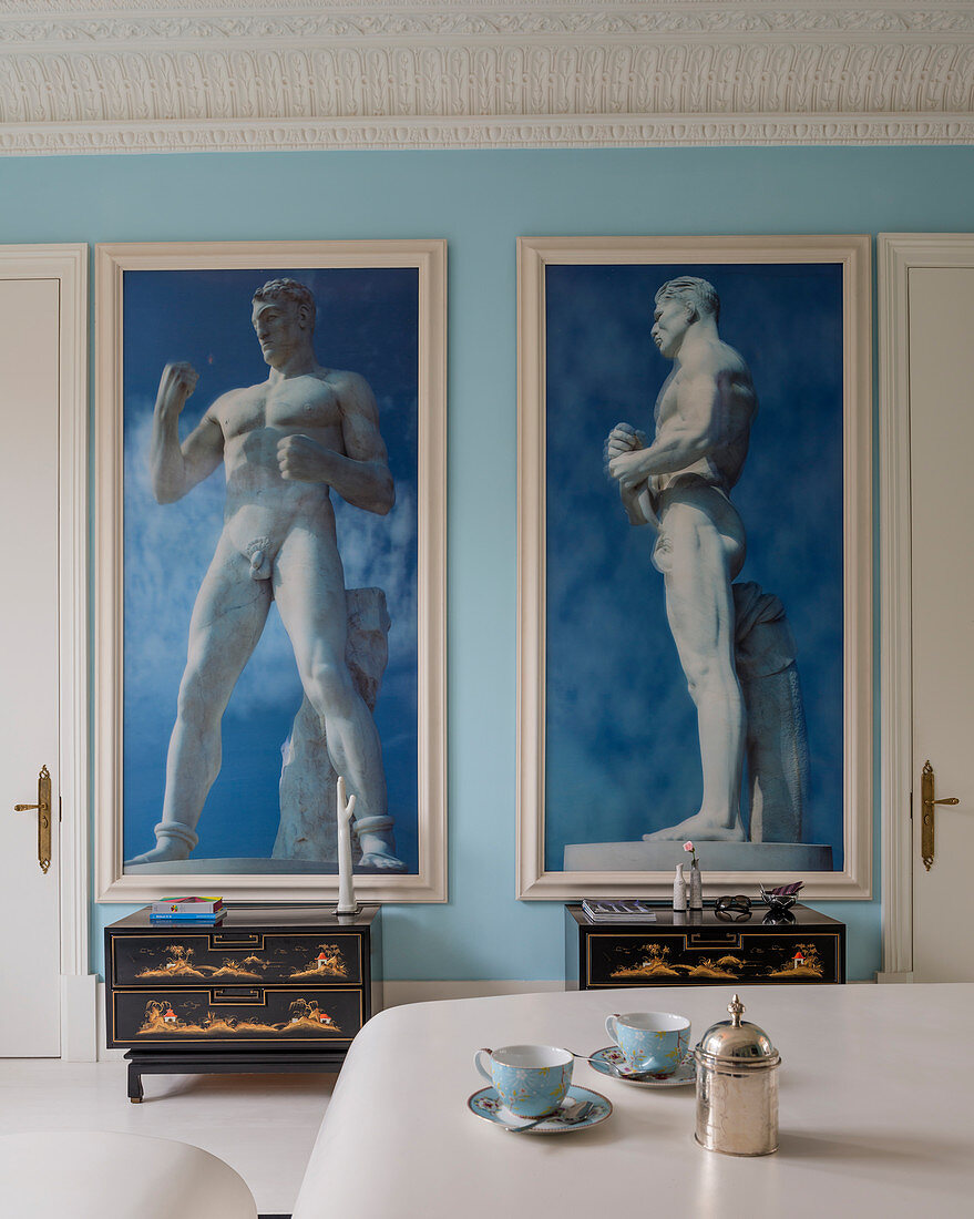 Two large framed photographs of classical sculptures on sky-blue wall