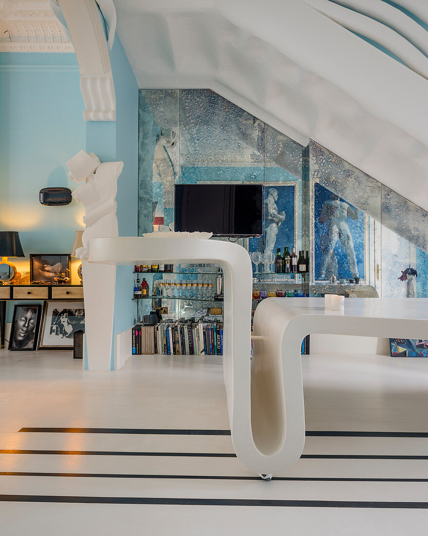 Gebogener Designertisch in extravagantem blauem Wohnraum mit Spiegelwand und Stuckaturen
