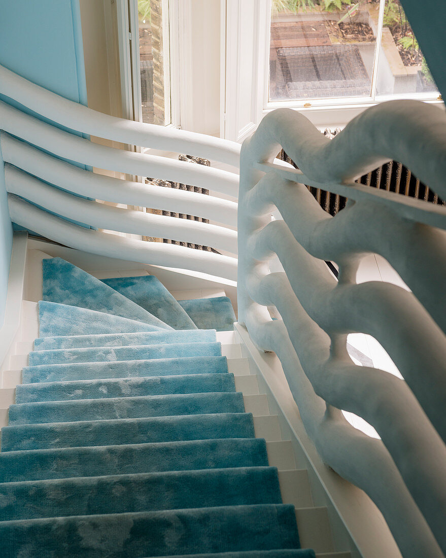 Treppe mit himmelblauem Läufer und skulpturalem Geländer in Weiß
