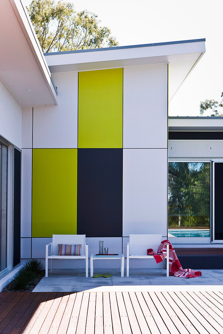 Sunny terrace in front of a house with colorful cladding