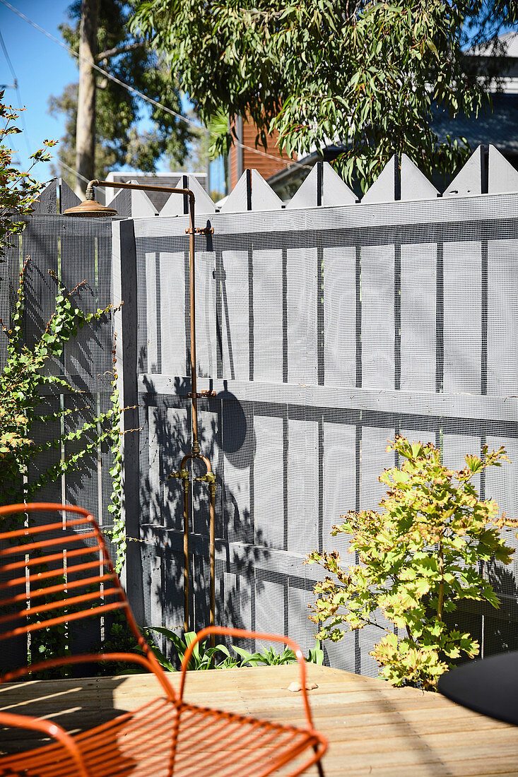Außendusche am Zaun im sonnigen Garten mit Terrasse