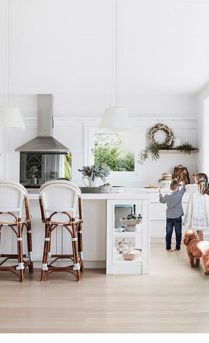 Children and dog in bright white kitchen with bar stools on kitchen island