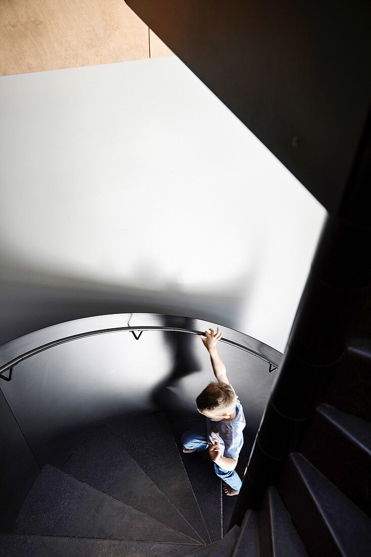 Boy on dark and modern spiral staircase
