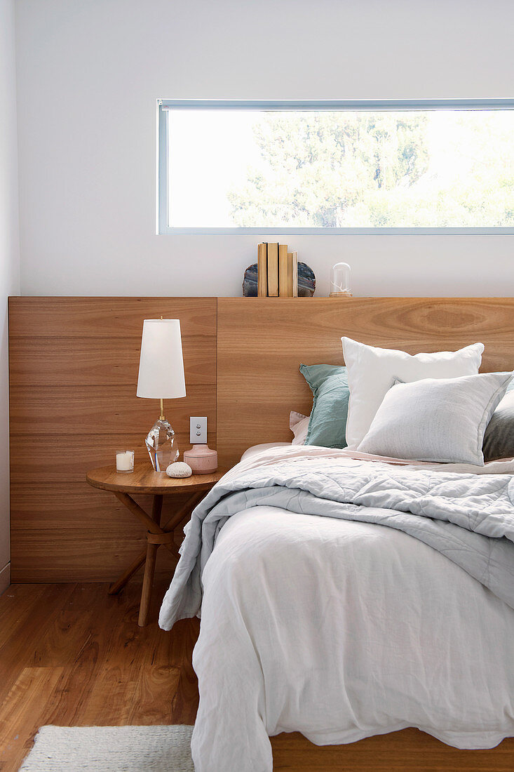 Bett mit Holzrückwand unter Fensterband