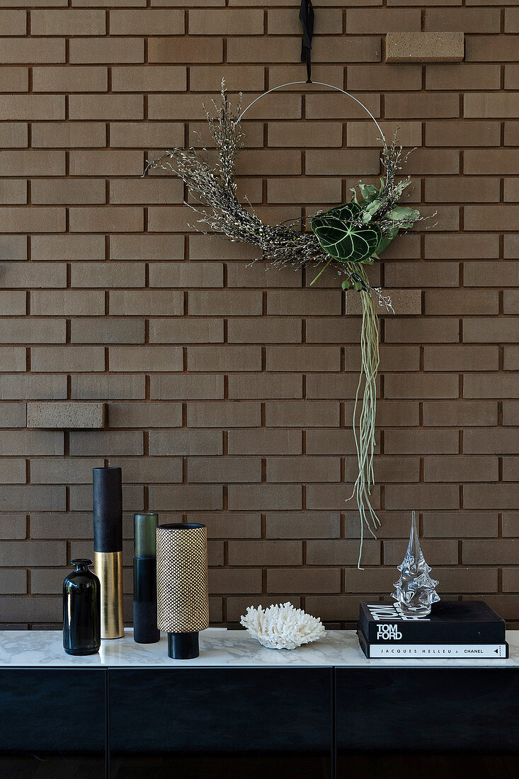 Minimalist wreath on the brick wall above the sideboard