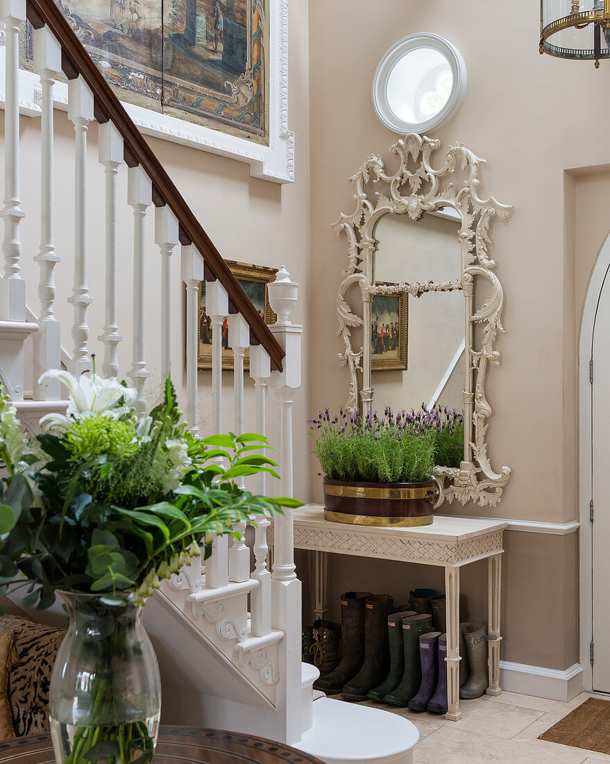 Ornate mirror above console table at foot of staircase in foyer
