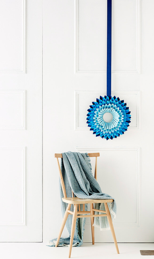 Blue paper star against white wall and chair with blanket
