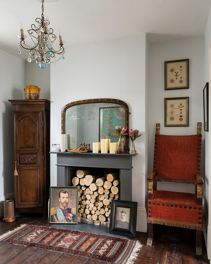 Firewood stacked in open fireplace surrounded by antique furniture