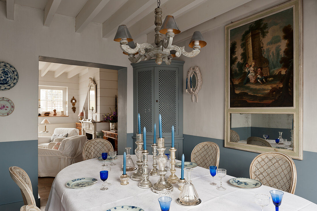 Silber Kerzenhalter auf gedecktem Esstisch, blauer Eckschrank und französischer Trumeau-Spiegel aus dem 18. Jahrhundert im Esszimmer