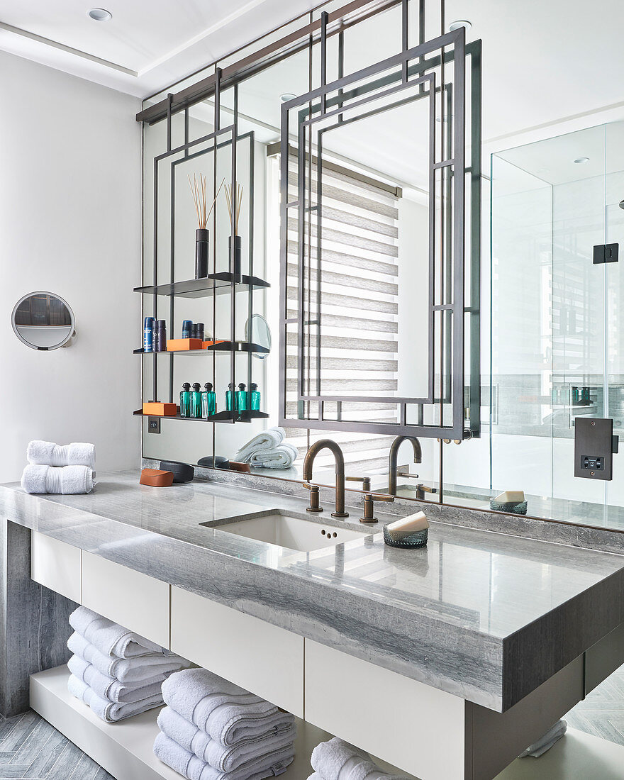 Metal frame and shelves on mirrored wall above washstand
