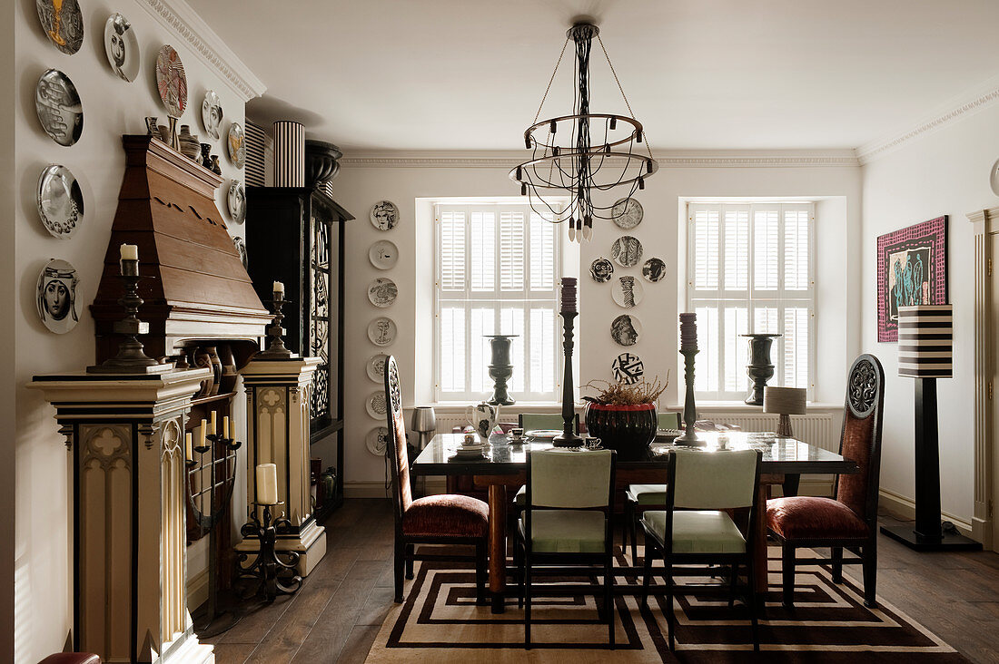 Designer chairs and mantelpiece decorated with pillars and decorative wall plates in stylish dining room
