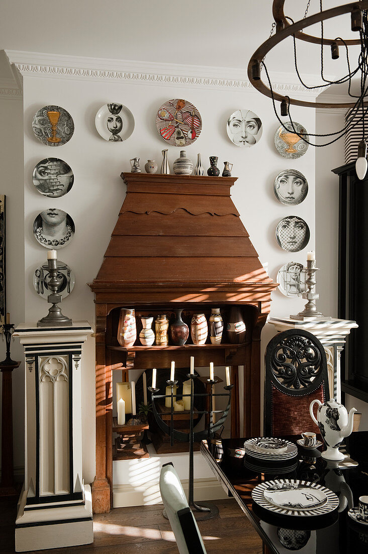 Hölzerner Kamin eklektisch dekoriert mit Säulen sowie Vasen- und Tellersammlung