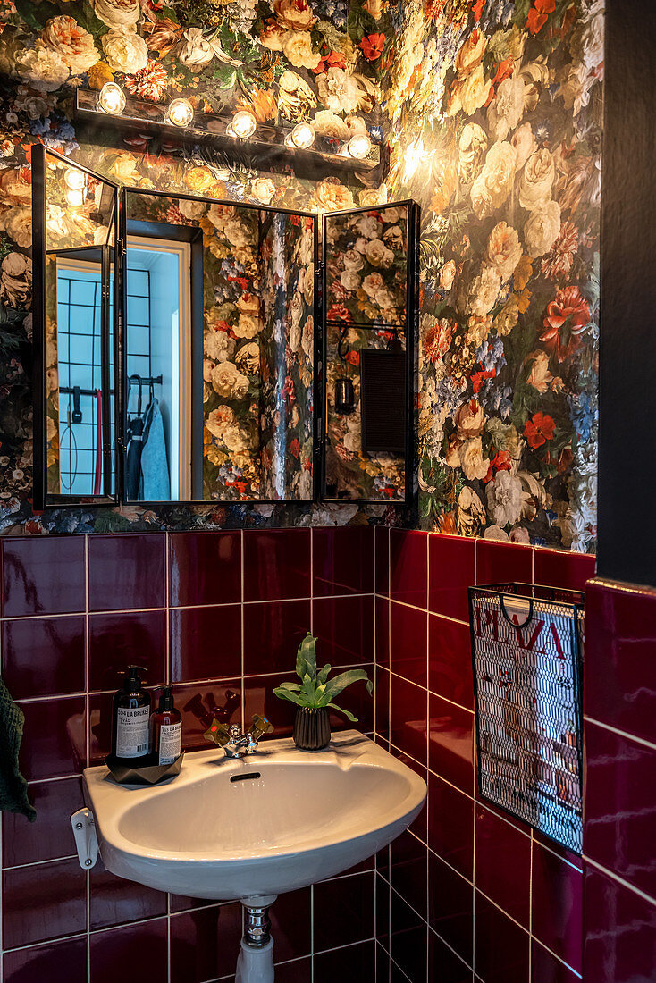 Handwaschbecken in Gäste-WC mit dunkelroten Fliesen und Blumentapete