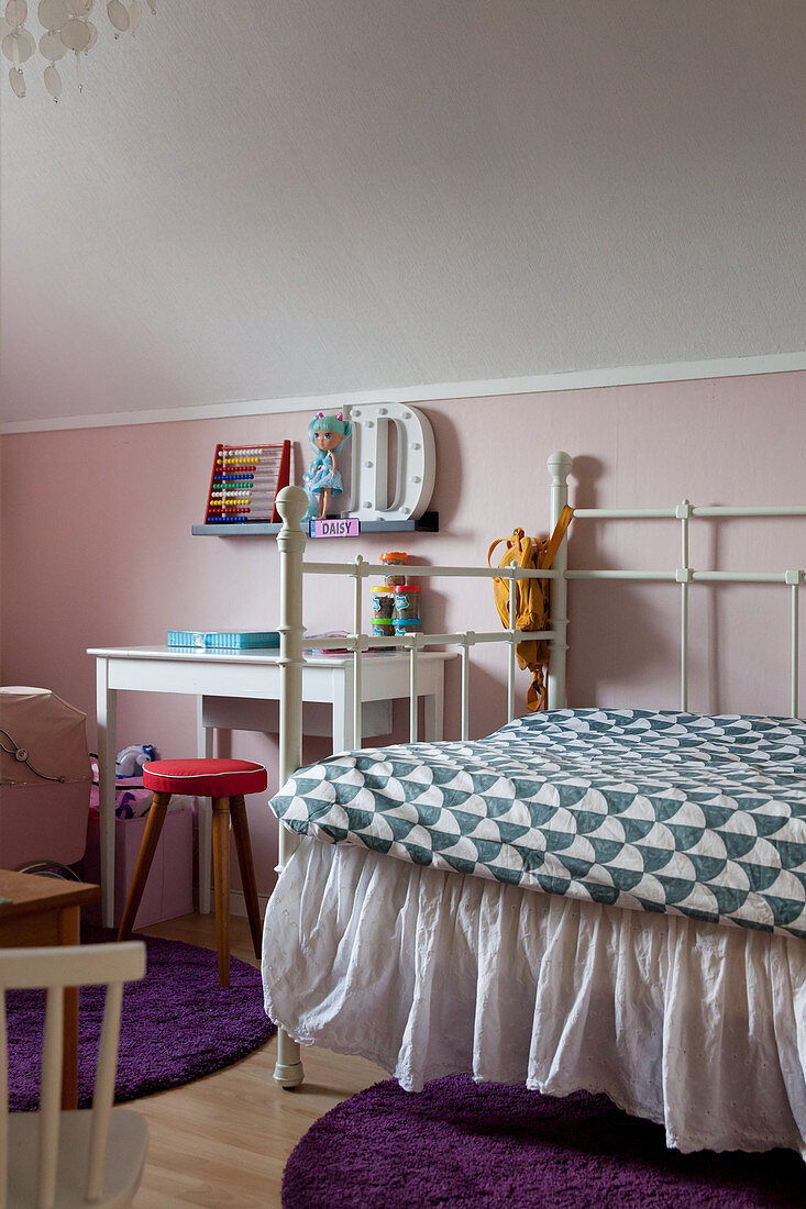 Metal bed with valance in child's bedroom with pink wall
