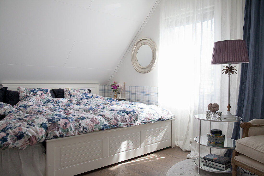 Elegant, blue-and-white bedroom below sloping ceiling