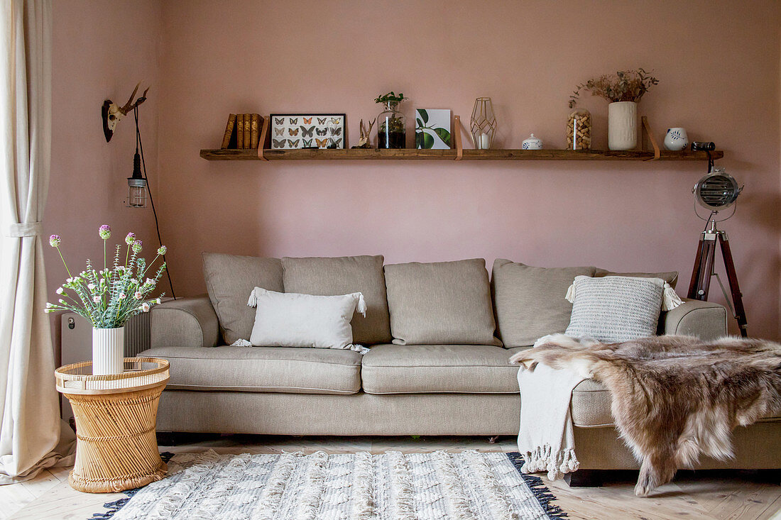 L-förmige Couch im Wohnzimmer mit pastellrosa Wänden
