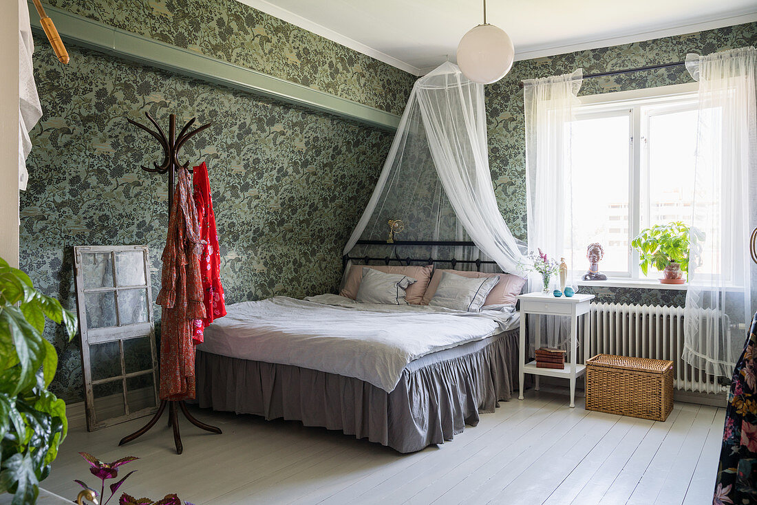 Bett mit Rüschen und Baldachin im Schlafzimmer mit Vintage-Tapete
