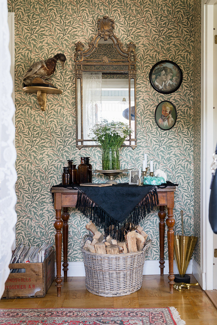 Old mirror and console table in hallway with vintage-style wallpaper