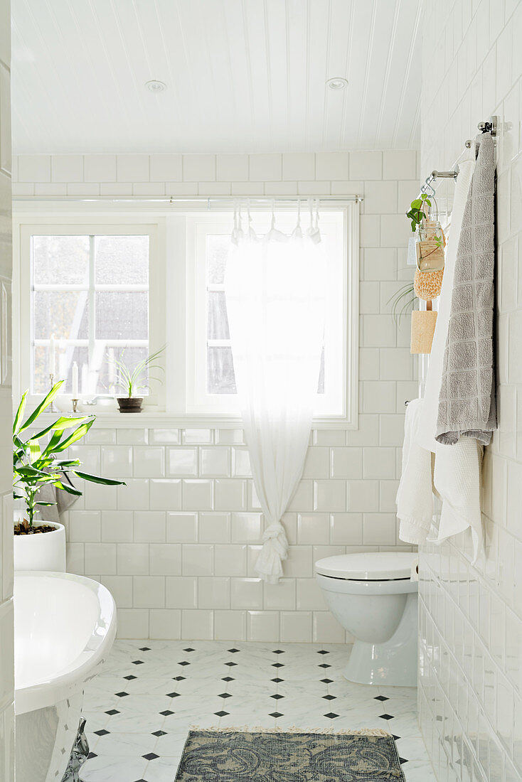 Free-standing bathtub and windows in bright bathroom