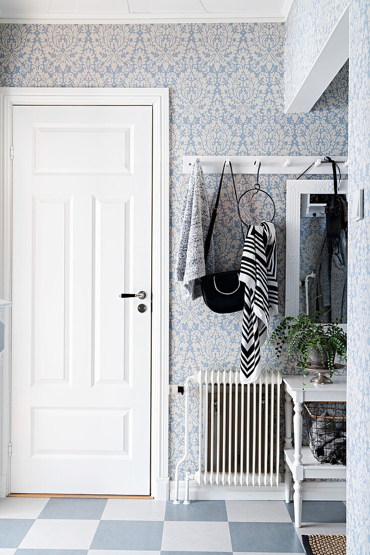 Blue patterned wallpaper and coat rack in foyer